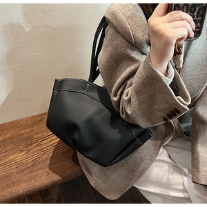 Detail of black pebbled leather tote bag with white contrast stitching and soft pleated base