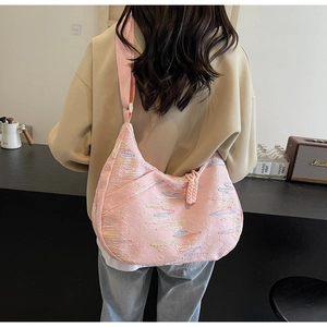 Pink canvas hobo bag with colorful stripes showing wide shoulder strap detail on a model