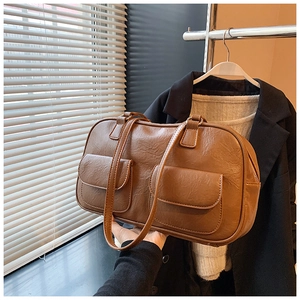Detail of a brown vintage tote bag featuring two front pockets and smooth leather texture