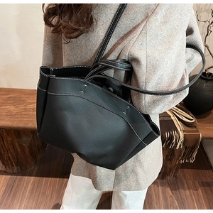 Close-up of black lychee leather tote bag featuring white contrast stitching details