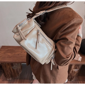 Gros plan d'un sac à bandoulière vintage beige avec pompons et plusieurs fermetures