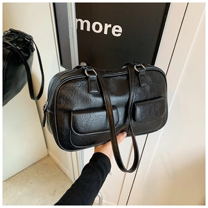 Detail shot of black retro textured leather handbag with two front flap pockets and glossy finish