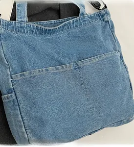 Detail view of washed blue denim tote bag featuring dual front pockets and twill texture