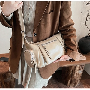 Détail du sac bandoulière en similicuir beige avec plusieurs poches zippées décoratives