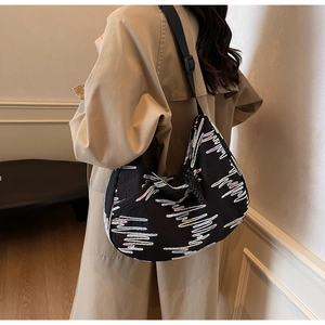 Detail of black dumpling bag with colorful wave embroidery and adjustable wide strap