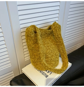 Detail of soft fuzzy mustard yellow bucket bag with plush faux fur texture and wide strap