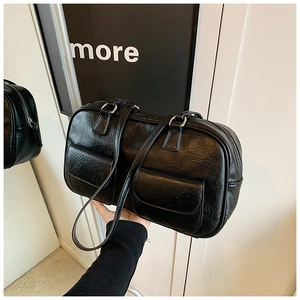 Detail of black leather Boston bag with retro texture, front flap pockets and long handles