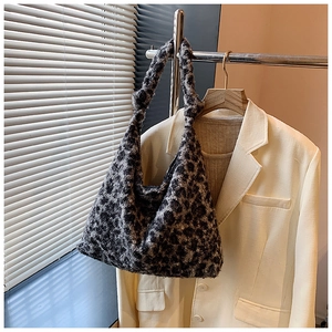 Close-up of leopard pattern plush tote bag hanging on a hanger with indoor soft lighting
