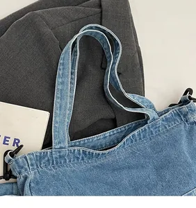 Detail of denim tote bag showing stitch texture, shoulder strap hooks and opening