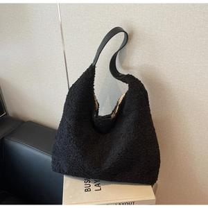 Gros plan d'un cabas noir en fausse fourrure pelucheuse avec sa bandoulière en cuir
