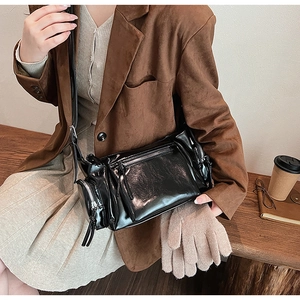 Vue détaillée d'un sac polochon vintage noir brillant avec fermetures éclair métalliques au porté