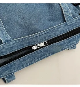 Close-up of smooth silver metal zipper and thick washed blue denim fabric on tote bag