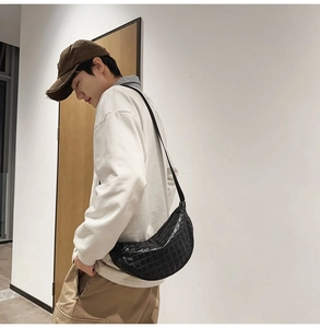 Detailansicht einer schwarzen gesteppten halbmondförmigen Umhängetasche aus Kunstleder