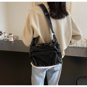 Close-up of black washed denim crossbody bag featuring multi-pocket design and wide strap