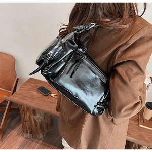 Gros plan détaillé d'un sac à bandoulière noir brillant avec poches et boucles en métal