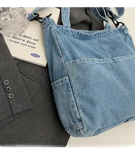 Detail of light blue denim tote bag featuring large pockets and adjustable shoulder strap