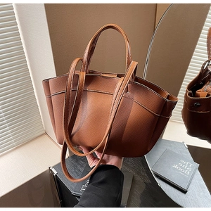 Detail of brown litchi pattern leather tote bag with unique folded wing design and dual straps