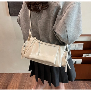 Détail du sac bandoulière en cuir brillant blanc crème avec poches multiples et franges