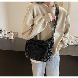 Detail of vintage black denim crossbody bag with functional multi-pockets and soft texture
