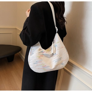 Close-up of white tote bag with colorful zigzag embroidery and wide shoulder strap