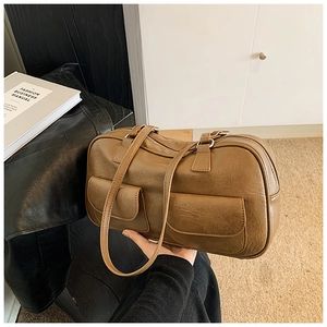 Detail of caramel vintage bowling bag with wrinkled leather texture and front pockets