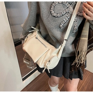 Détail d'un sac bandoulière blanc crème en cuir souple avec lacets et poche zippée