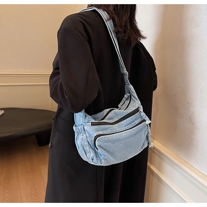 Macro detail of washed denim fabric layers and functional zippers on a crossbody bag