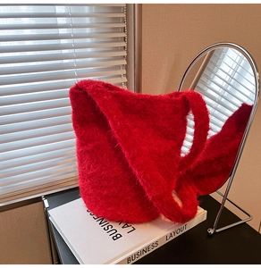 Close-up of fluffy bright red plush bucket bag showing soft faux mohair texture and wide strap
