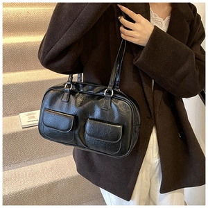 Close-up of a black vintage glossy leather shoulder bag with double front pocket details