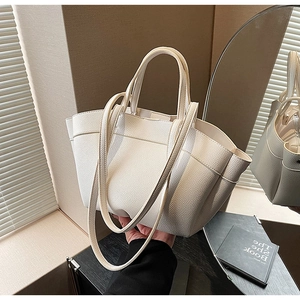 Detail of white pebble-textured leather tote bag with handle and side fold design
