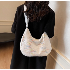 Detail of white hobo bag with colorful wavy embroidery and wide nylon strap