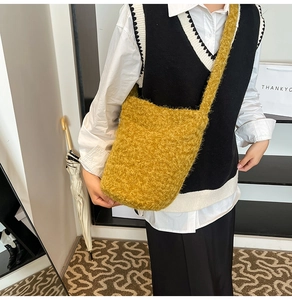 Detailed plush texture of a yellow fuzzy bucket bag worn by a model in casual outfit