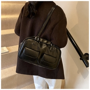 Retro black glossy PU shoulder bag with two front pockets shown on model at a side view