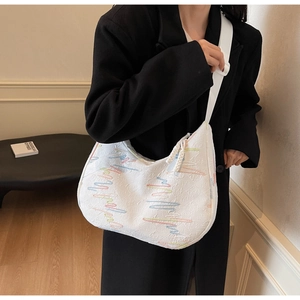 Close-up of white hobo bag with colorful wave embroidery and wide strap detail