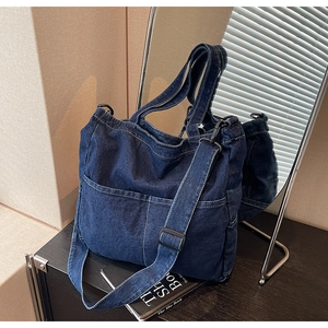 Detail of blue denim tote bag showing white contrast stitching and front pockets