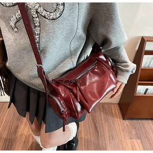 Vue détaillée du sac bandoulière vintage rouge foncé avec finition brillante et glands