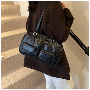 Detail of a vintage black leather tote bag with dual front flap pockets and smooth finish