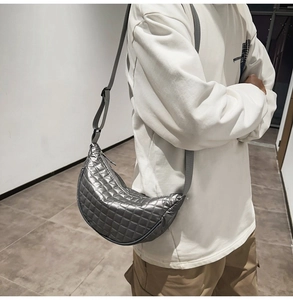 Makroansicht der metallisch silbernen Stepptasche mit verstellbarem breitem Gurt am Modell