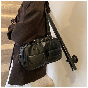 Detail of black shoulder bag with dual front pockets and silver zipper on a model
