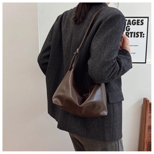 Brown leather hobo bag styled as a shoulder bag on a model wearing a grey blazer