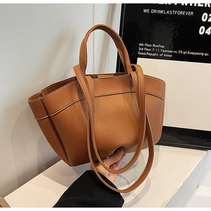 Detailed view of brown lychee grain leather tote bag with stylish side fold design