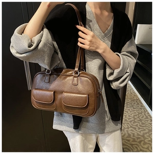 Detail of vintage brown textured shoulder bag showing front pockets and zipper closure