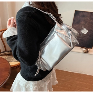 Sac bandoulière argenté Y2K avec poches zippées porté par un mannequin en intérieur