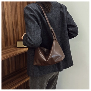 Detail of a vintage dark brown Hobo shoulder bag worn by a model in an office setting