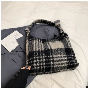 Detail shot of the plush plaid texture and integrated shoulder strap of a large tote bag