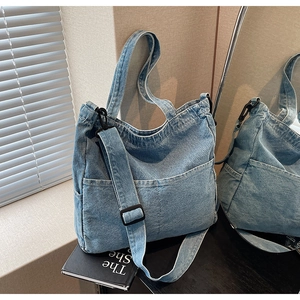 Detail of light blue denim tote bag with functional front pockets and adjustable strap