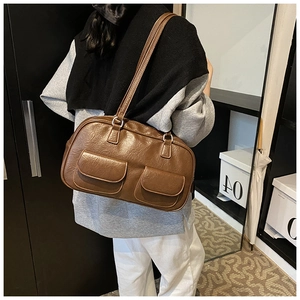 Detail view of a vintage brown shoulder bag with double flap pockets and textured leather