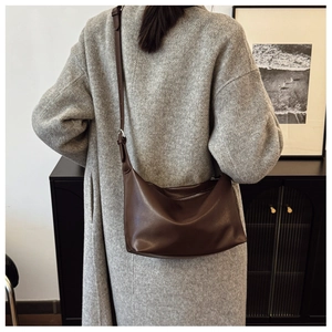 Detail view of dark brown PU leather half-moon shoulder bag styled with a wool coat