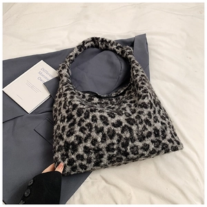 Detailed view of plush leopard print tote bag on white fabric with fashion accessories