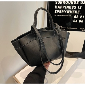 Close-up of black litchi grain leather tote bag with white contrast stitching details